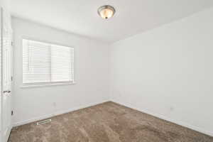 Carpeted spare room featuring baseboards