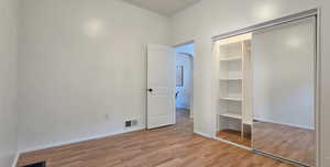 Unfurnished bedroom with light wood-type flooring, arched walkways, and a closet