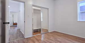 Unfurnished bedroom with light wood-style floors, multiple windows, and a closet