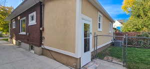 View of side of home featuring stucco siding and a gate