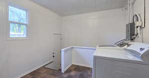 Laundry area featuring a wainscoted wall, electric panel, washer and dryer, and stone finish flooring