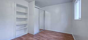 Unfurnished bedroom featuring dark wood finished floors, a textured wall, and a closet