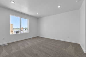 Empty room with carpet flooring, recessed lighting, and a textured ceiling