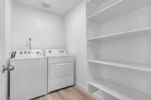 Washroom featuring light wood finished floors and washing machine and dryer