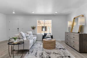 Living room with light wood-type flooring, a textured ceiling, and recessed lighting