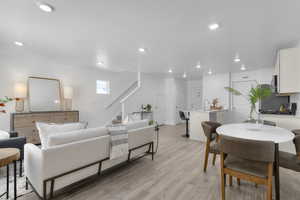 Living area with stairs, light wood-type flooring, recessed lighting, and a textured ceiling