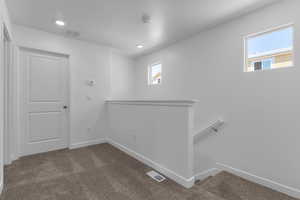 Hall with an upstairs landing, dark colored carpet, a textured ceiling, and recessed lighting