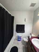 Full bathroom featuring vanity, a textured ceiling, tile patterned flooring, and shower / tub combo