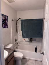 Bathroom with a textured ceiling, light tile patterned floors, vanity, and shower / bath combination