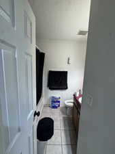 Bathroom featuring vanity, light tile patterned floors, a textured ceiling, and shower / tub combo with curtain