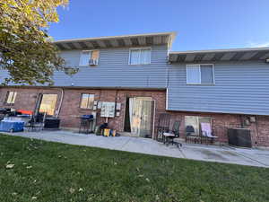 Rear view of property with a patio, a yard, and brick siding