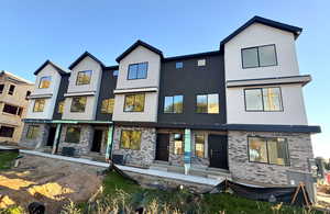 Rear view of property featuring brick siding, stucco siding, and a patio