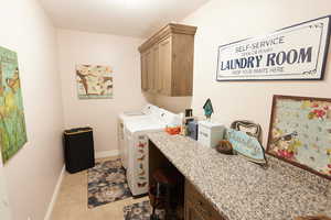 Laundry area featuring cabinet space, independent washer and dryer, light tile patterned floors, and an office area