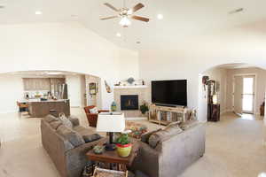 Living room featuring arched walkways, recessed lighting, ceiling fan, high vaulted ceiling, and light carpet