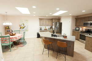 Kitchen with a skylight, appliances with stainless steel finishes, recessed lighting, light stone countertops, and a breakfast bar