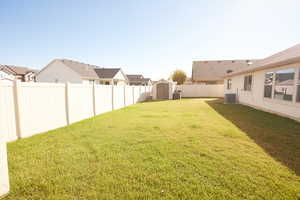 Fenced backyard featuring a storage shed and a residential view