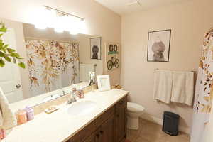 Full bathroom with light tile patterned floors, vanity, and curtained shower