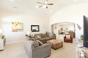 Living room featuring arched walkways, light colored carpet, ceiling fan, high vaulted ceiling, and recessed lighting