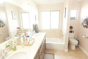 Bathroom with light tile patterned floors, double vanity, and a bath