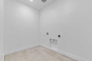 Laundry area featuring electric dryer hookup, washer hookup, and light tile patterned floors