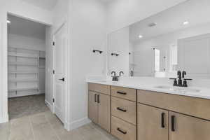 Full bath featuring a spacious closet, double vanity, light tile patterned floors, recessed lighting, and light carpet