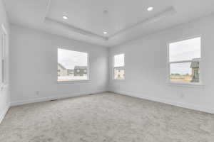 Unfurnished room with a tray ceiling, light colored carpet, and recessed lighting
