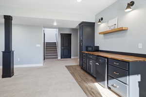 Dry bar featuring butcher block counters, open shelves, recessed lighting, light carpet and tile flooring inset