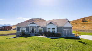 View of front of house featuring a mountain view, a front yard, a garage, and concrete driveway
