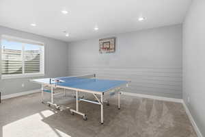 Rec room adjacent to the downstairs living area with light carpet and recessed lighting