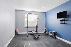 Workout area with dark rubber floors, a textured ceiling, and recessed lighting