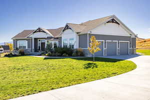 Craftsman-style home featuring stone siding, concrete driveway, a front yard, and an attached 3-car garage