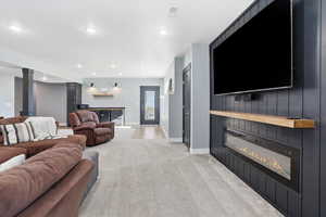 Living area featuring light colored carpet, recessed lighting, sconce lighting, exterior door to the patio, and a large fireplace