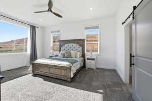 Primary bedroom with a barn door, ceiling fan, carpet, and recessed lighting