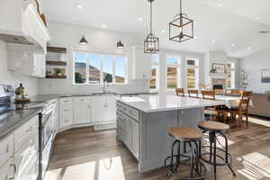 Kitchen with electric stove, gray cabinetry, center island, under cabinet range hood, and tasteful backsplash