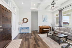 Formal sitting room with coffered ceiling, plenty of natural light, dark wood finished floors, and recessed lighting