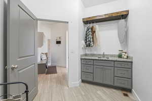Laundry room sink with grey cabinets and tiled floors.  Also mudroom.