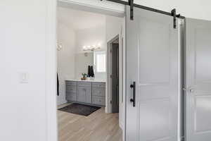 Full bath in the primary suite featuring barn door, vanity and wood tiled floors