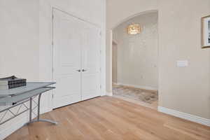 Unfurnished office with light wood finished floors, arched walkways, and a chandelier