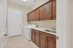 Laundry room with cabinet space, light tile patterned floors, and separate washer and dryer