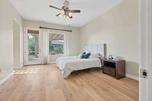 Bedroom with access to outside, light wood-style flooring, a ceiling fan, and arched walkways
