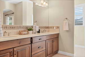Bathroom featuring double vanity, light tile patterned flooring, and backsplash