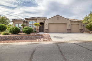 Mediterranean / spanish-style house with stone siding, a garage, driveway, and stucco siding