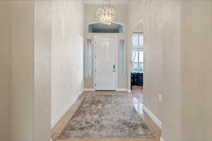 Entryway with a chandelier, arched walkways, light tile patterned floors, and a textured wall