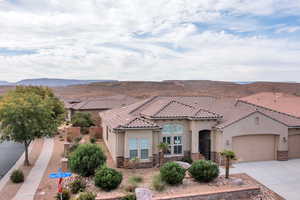 Mediterranean / spanish house with a garage, stone siding, concrete driveway, stucco siding, and a mountain view