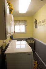 Laundry room with wainscoting, a textured ceiling, cabinet space, and washing machine and dryer