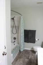 Bathroom with dark wood-type flooring, vanity, and shower / bath combo with shower curtain