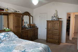 Bedroom featuring light colored carpet, lofted ceiling, and a ceiling fan