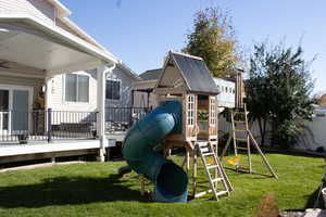 View of playground featuring a lawn and a wooden deck