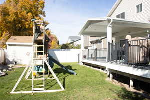 Fenced backyard featuring a wooden deck and a playground