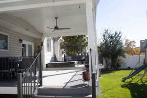 View of patio / terrace featuring a playground, a ceiling fan, a hot tub, and a deck